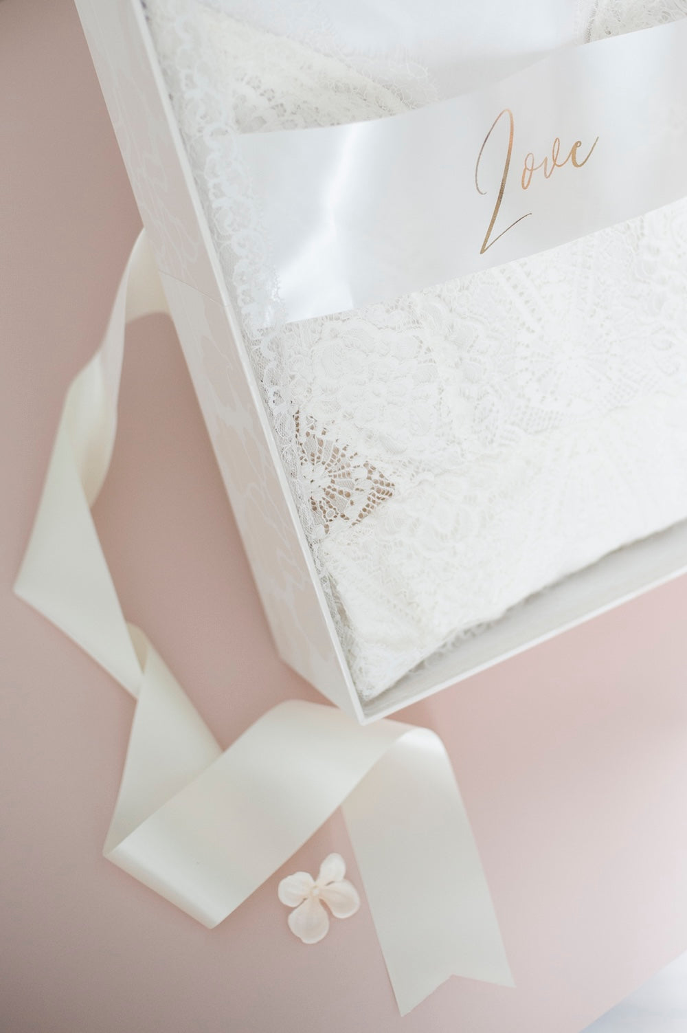 White wedding dress box with a bow and 'Love' card on a pink background.